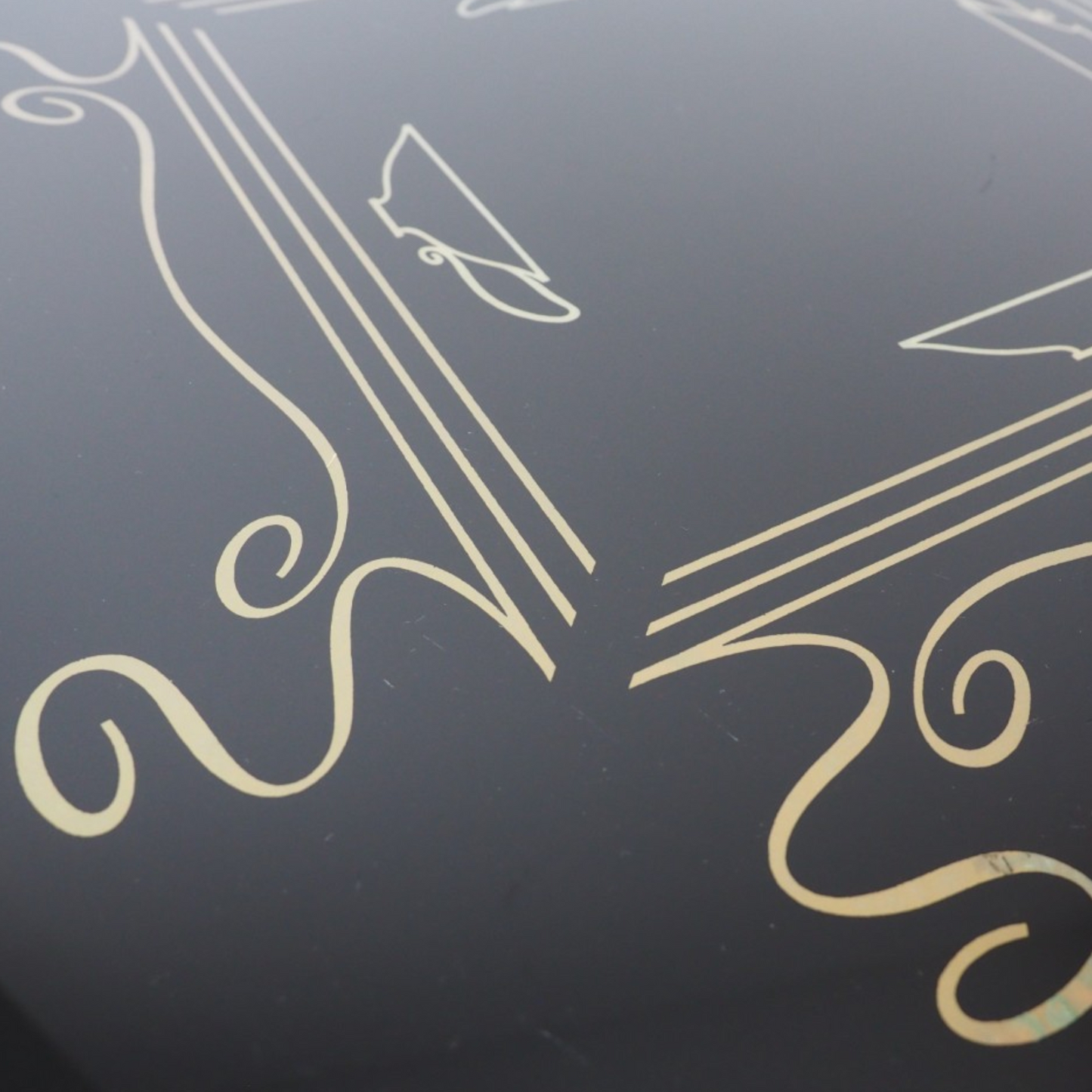 Zbliżenie na złoty wzór z motywem kawy na czarnym szklanym blacie stolika Alburette Busch