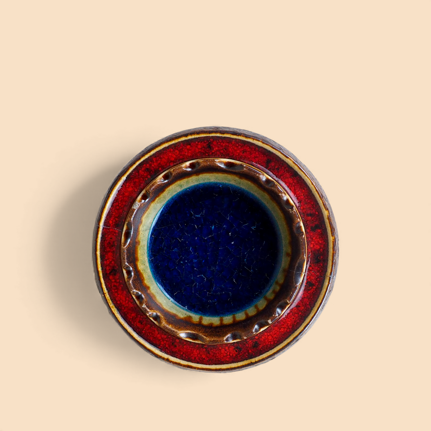 Popielniczka fat lava West Germany z niebieskim szkłem crackle, koncentryczne kręgi czerwone i tęczowe, widok z góry
