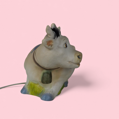 Lampka nocna Heico krowa, widok z trzech czwartych z zieloną trawą i niebieskimi łatami