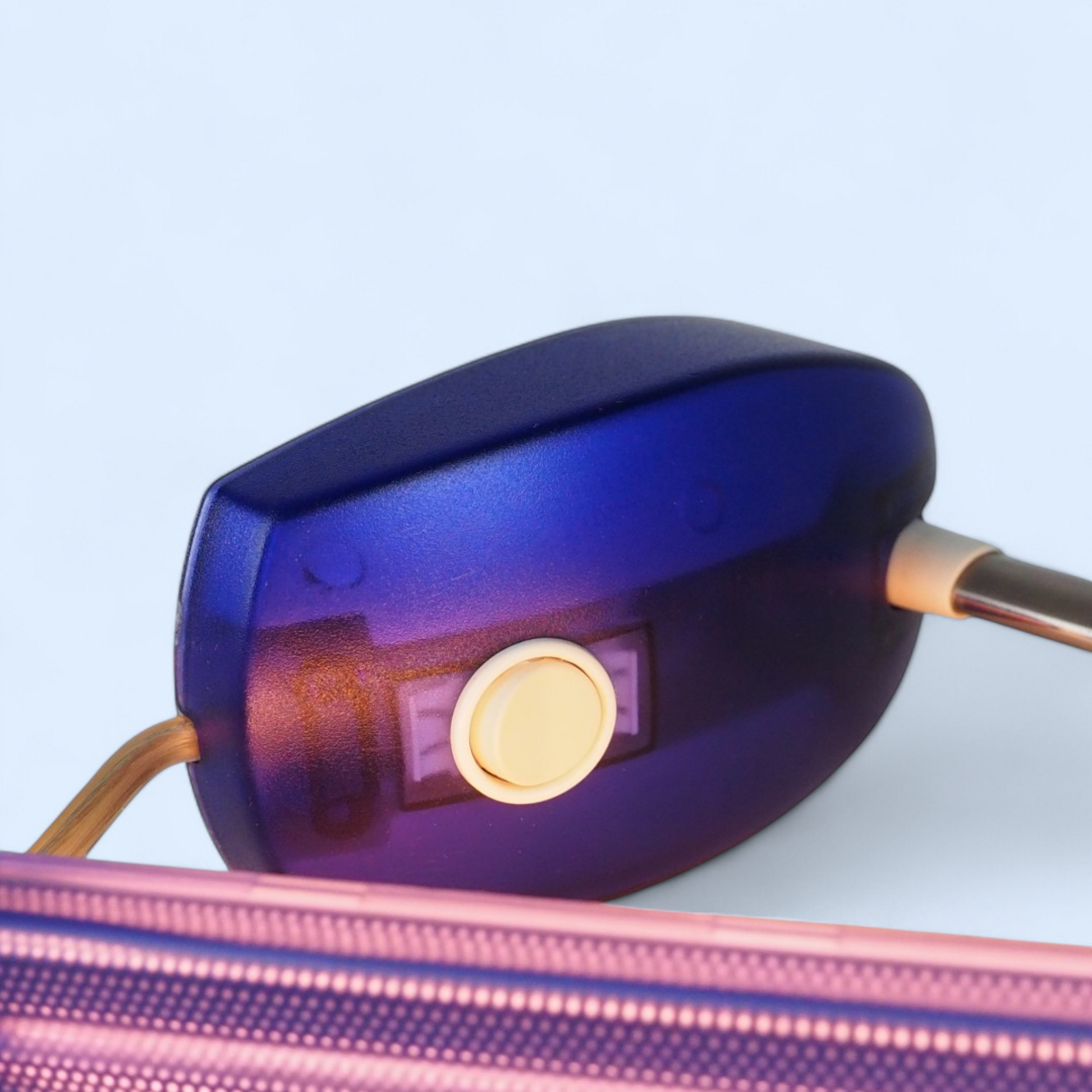 Niebieska podstawa Microlight Artemide zbliżenie, widoczny przycisk włącznika i włączony klosz